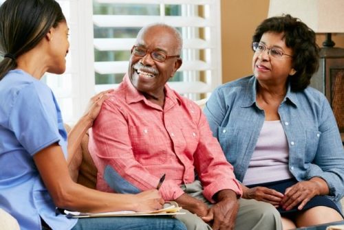 Caregiver sitting with a senior couple LT